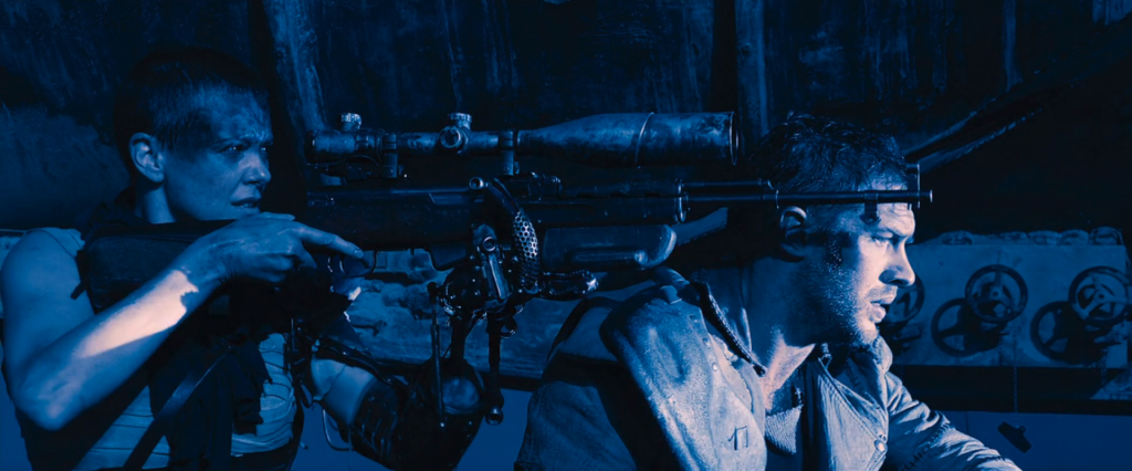 Furiosa uses Max's shoulder to steady a rifle as she prepares to take a shot.